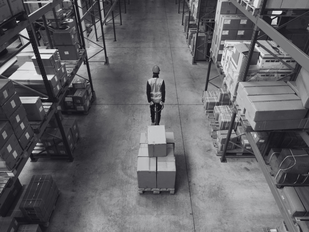 employé d'entrepot tirant des cartons avec un chariot